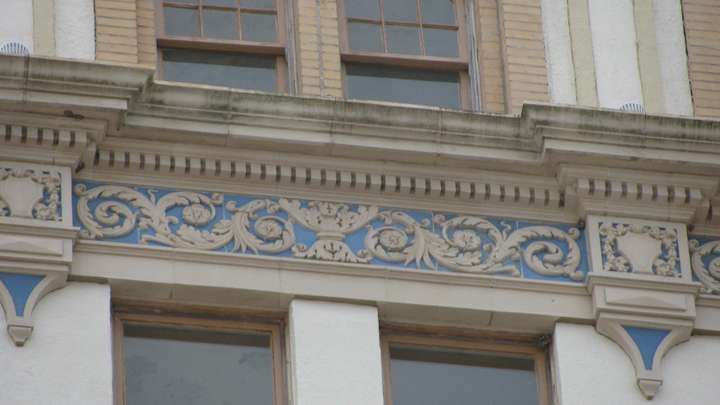 A close up of trim, showing intricate tan designs of leaves overtop a blue tile background