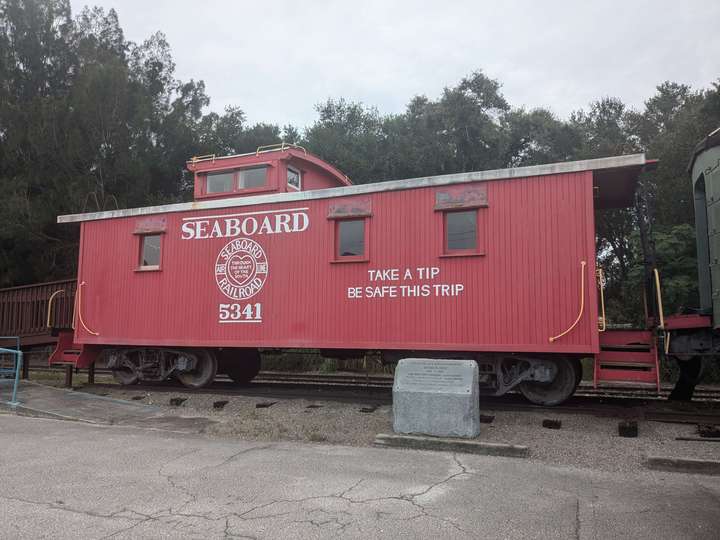 A red wooden caboose with an offset cupola. Text on the side says 