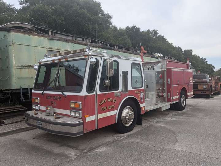 A small firetruck from the 1980s or 90s, painted in a standard red and white paint scheme. 