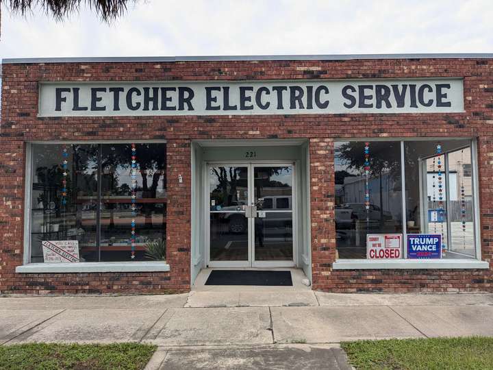 A small brick electronics store with two large display windows either side