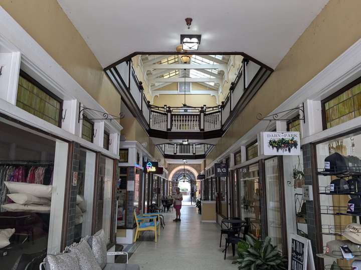 The interior of a 2-story shopping arcade. It's painted a sand color with white and black accents on the window frames and other trim. The 2nd floor is visible between the walkways.