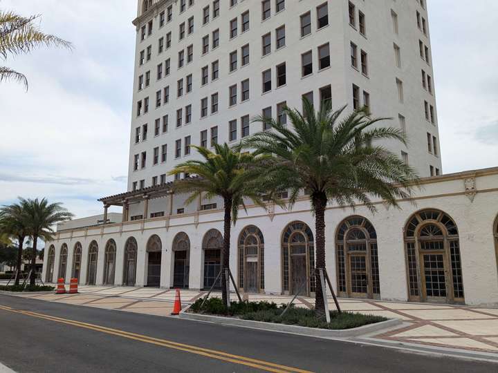 A closer view of the first floor, which has repeating arched, wood framed doors and windows along it's length