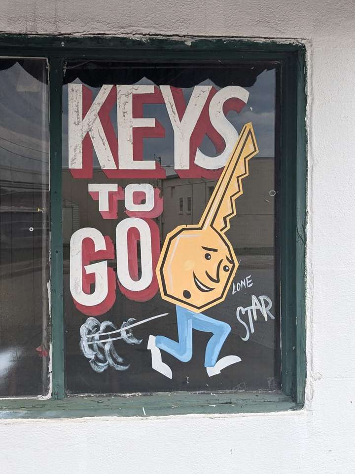 A painted window sign featuring a design of a key with a face and legs