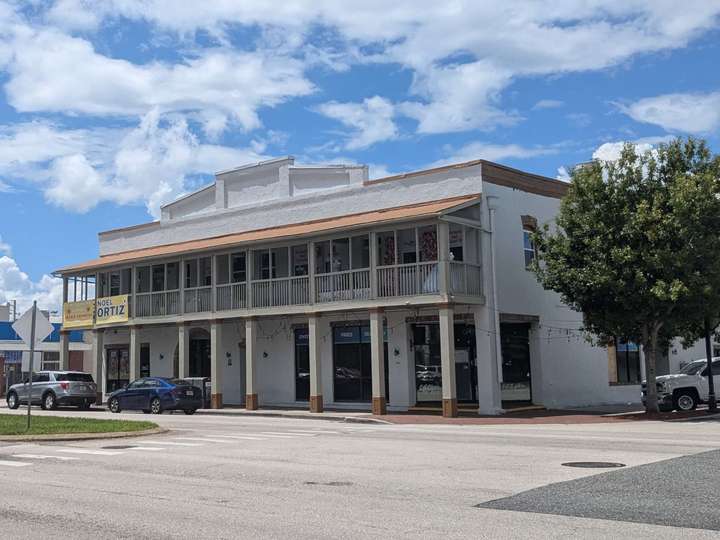 an off-white 2-story building with an elevated porch running the whole length