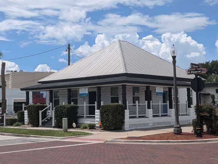 a brick house with a metal central-peak roof and a wraparound porch