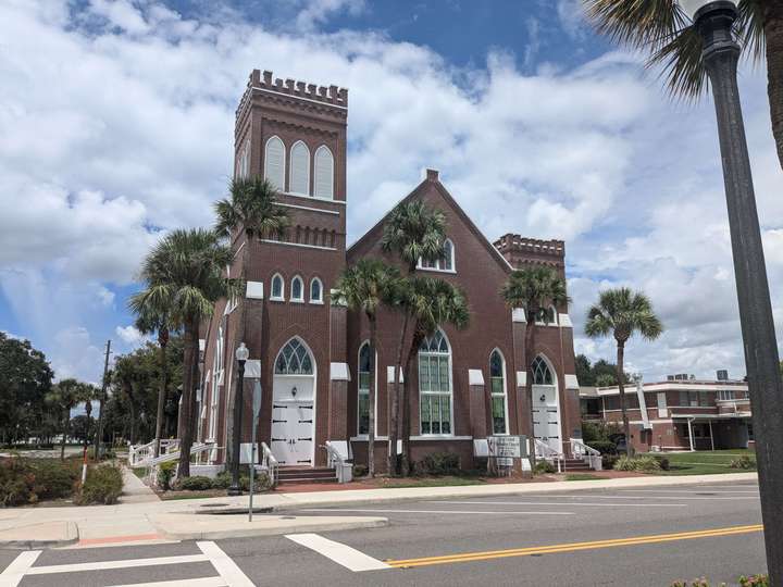 a castle-esque red brick church with white windows & trim