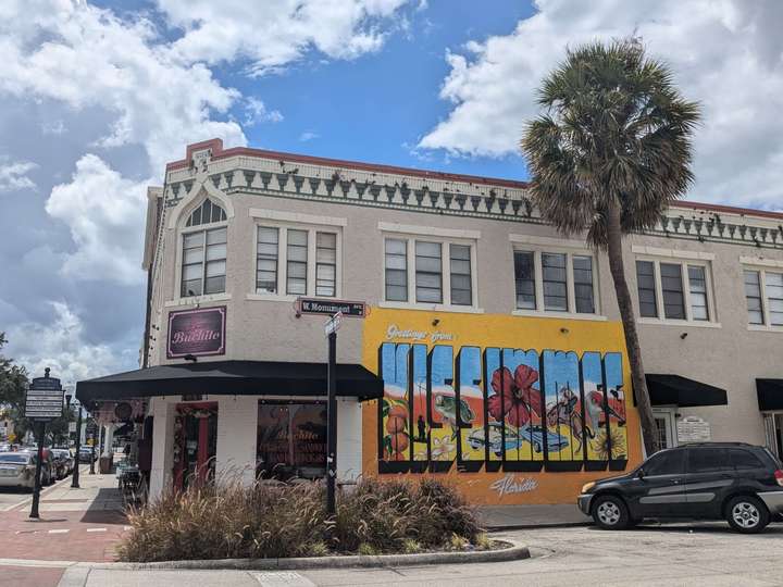 The side of an off-white corner building, with a medium mural