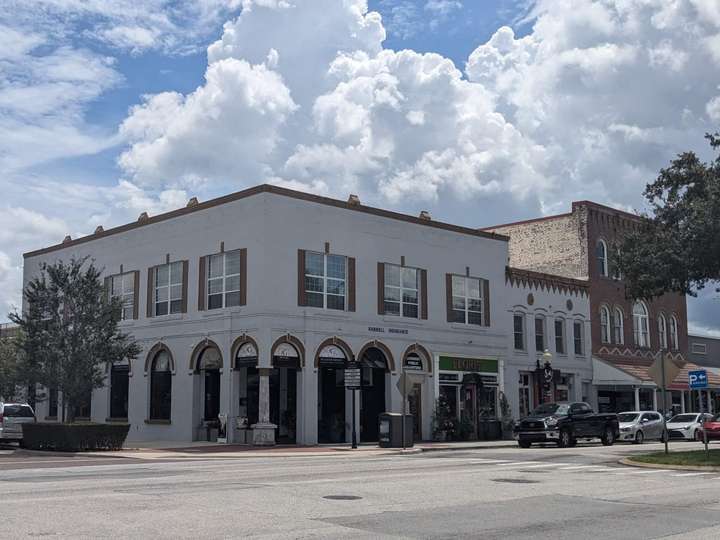 a white 2-story corner building, with arches on the ground floor.