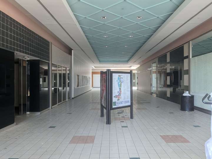 An entirely vacant 90s mall corridor, with a directory in the foreground