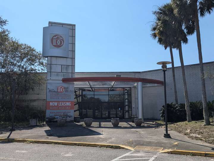 A grimey plyon sign with a silver box containing an IDO logo next to a mall entrance