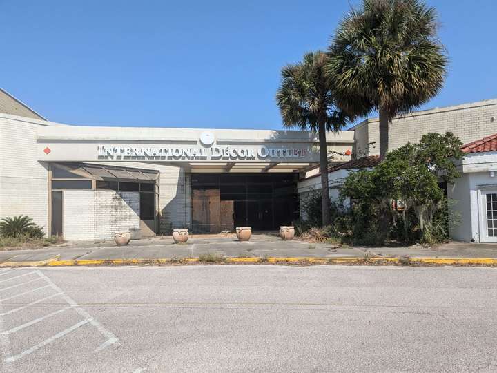 A partially boarded up and overgrown mall entrance