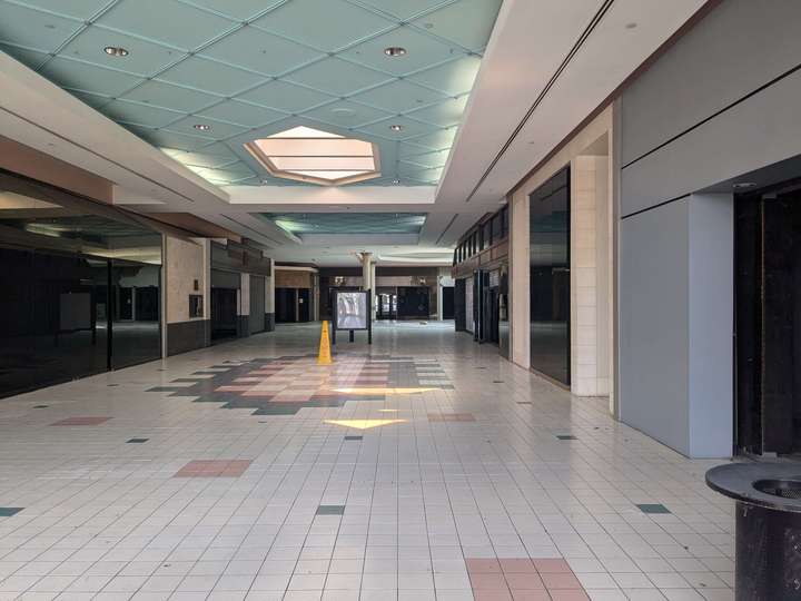 An entirely vacant 90s mall corridor, with a directory in the background