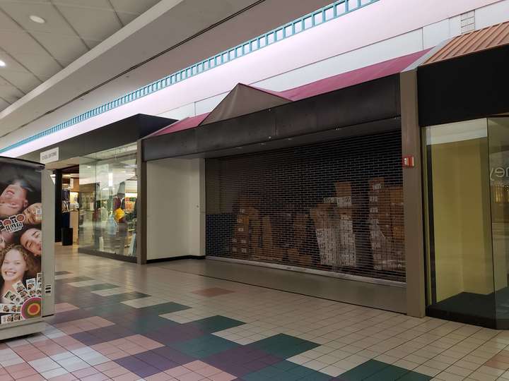 A vacant black storefront with a peaked center and a mauve roof