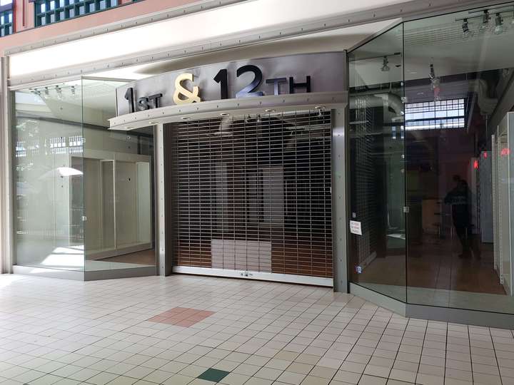 A vacant clothing store with glass bay windows on either side