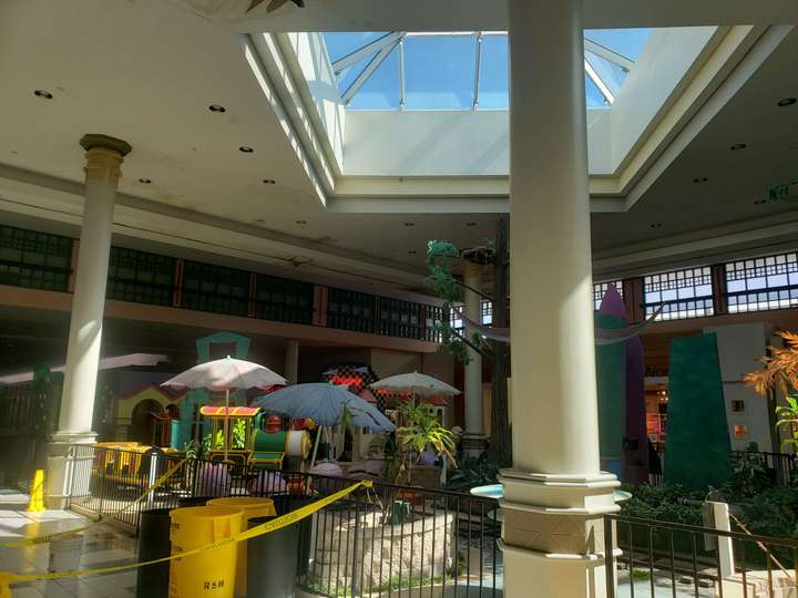 a mall skylight framed by pillars, above a nonfunctional kids train ride