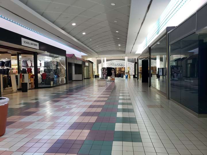 A view down a mall corridor, with dark teal, pink, and purple tiles