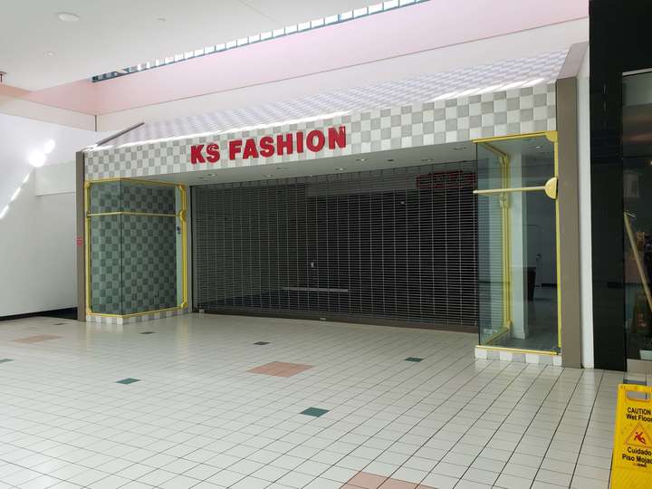 A vacant storefront with a checkerboard pattern and thick gold window trim