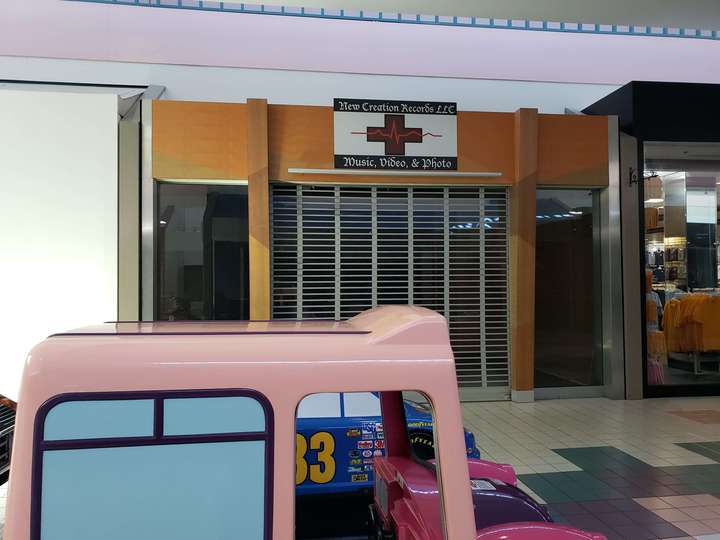 A vacant dark yellow-orange and brown storefront, behind a kiddie ride