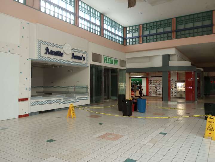 a vacant pretzel store and clothing store, behind roped off trash cans