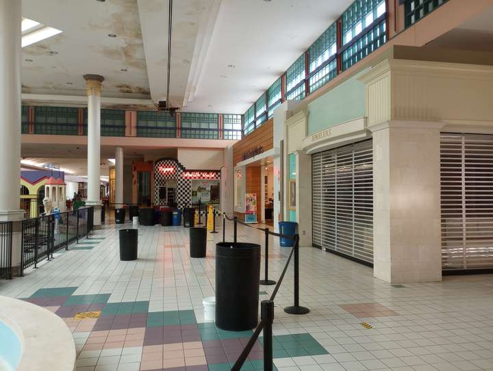 a hole in the ceiling and trashcans to catch water, in front of a bath & body works