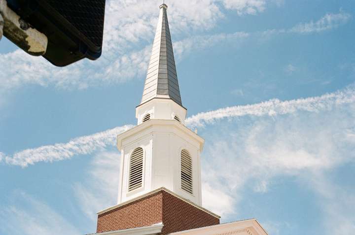 A white church spire with a green peak