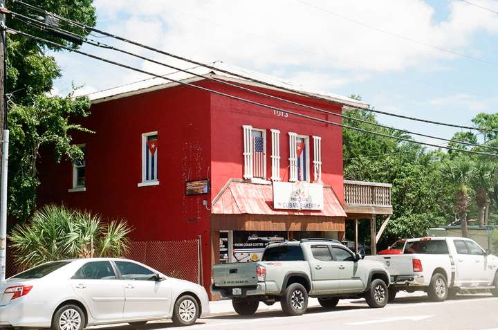 A square, red two story building with Cuban and American flags in the upper windows