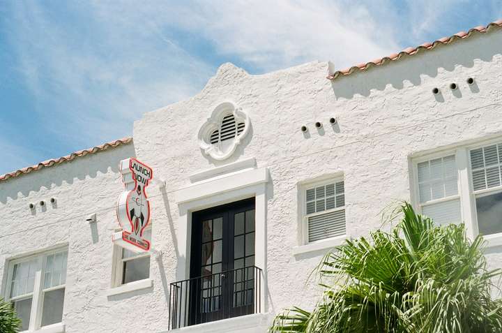 the upper floor of a white stucco building, with a small balcony