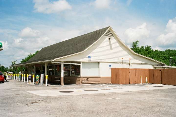 An old wooden convenience store with a tall roof that sweeps up to peak along the center