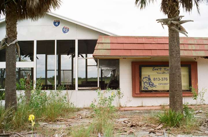 A view of that seating area as well as a sign to its side, framed by palm trees