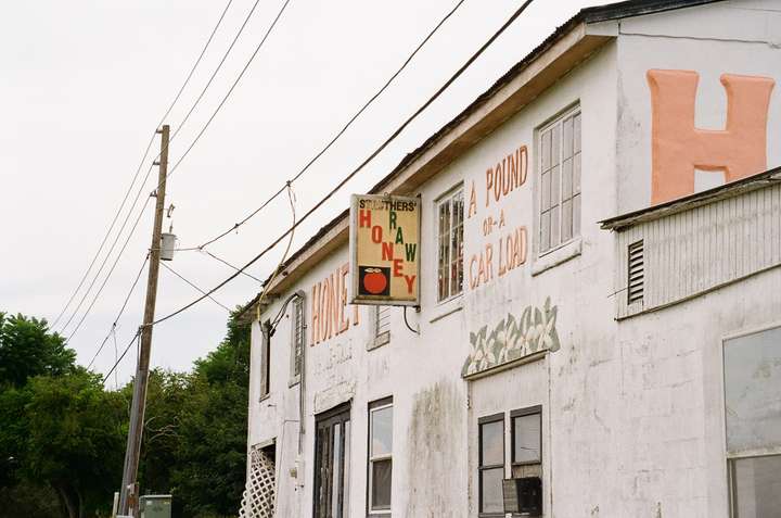 a vintage plastic panel sign, on the side of a weather beaten building