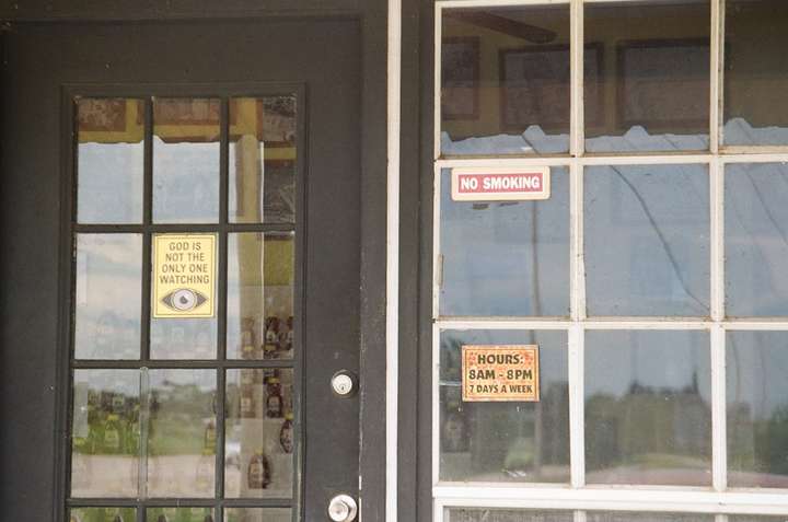 A black windowed door and a white window with various signs in them