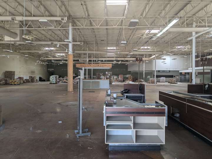 A stripped out grocery store interior. Checkouts and other assorted detritus are visible