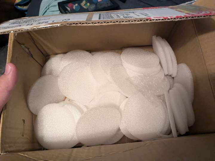 a cardboard box full of thin foam circles