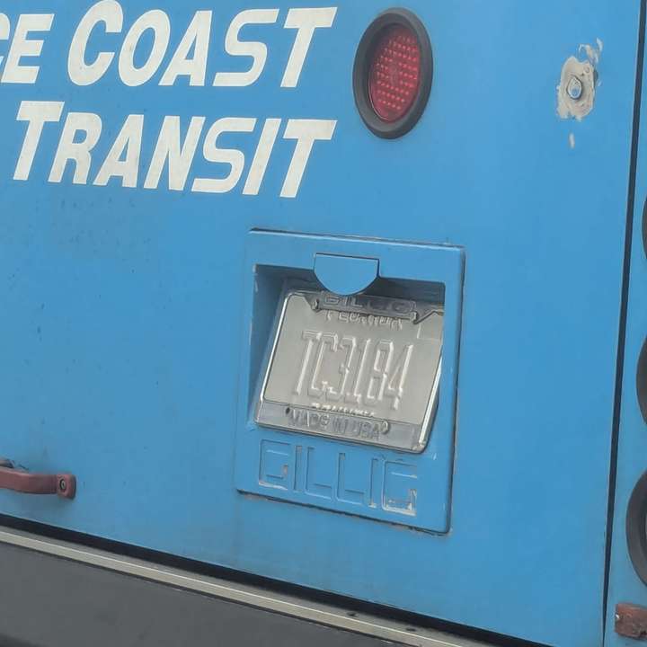 A zoomed in view of a bare metal license plate on a bus