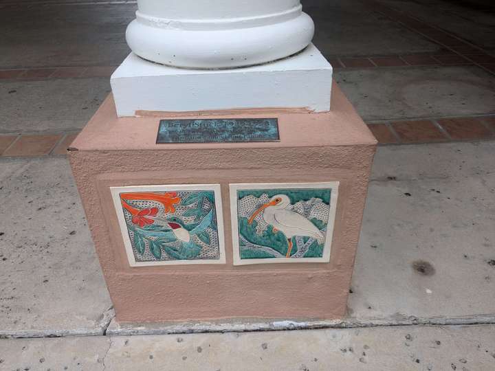 two tiles with bird art embedded in the bottom of a pillar