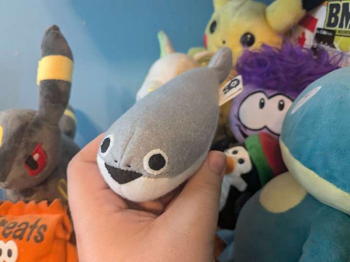 A small plush Sacabambaspis held in front of a pile of other plush