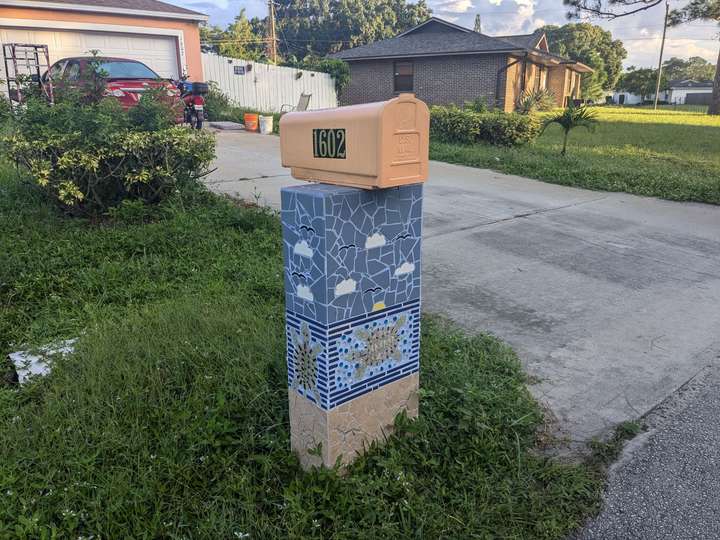 A mailbox decorated with a tile mosaic of clouds and sea turtles