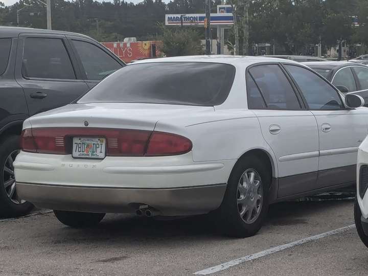 A white sedan with full-width red tail lights