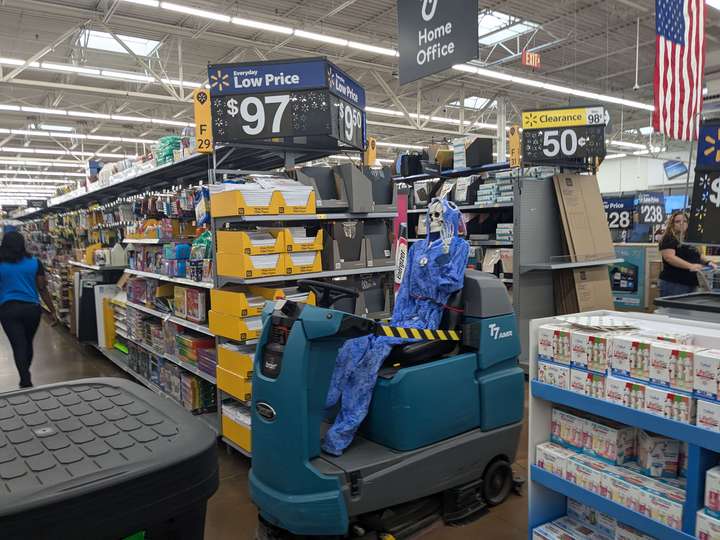 A plastic skeleton wearing Stitch pajamas, buckled onto an automated floor scrubber