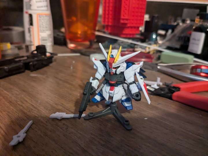 a small chibi gundam on a cluttered work desk