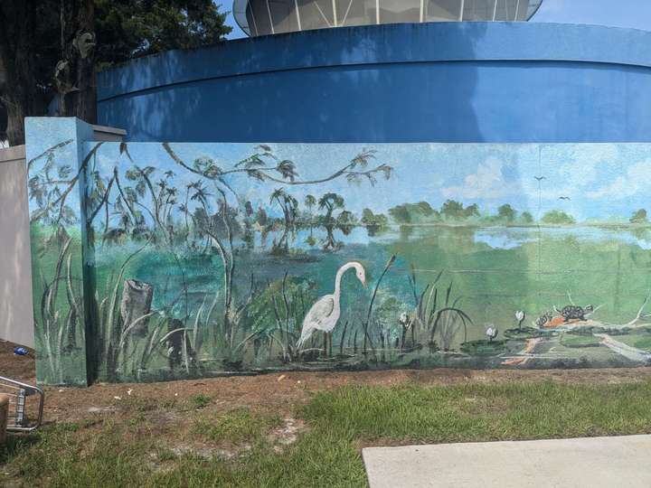 A mural of marshland on a concrete fence