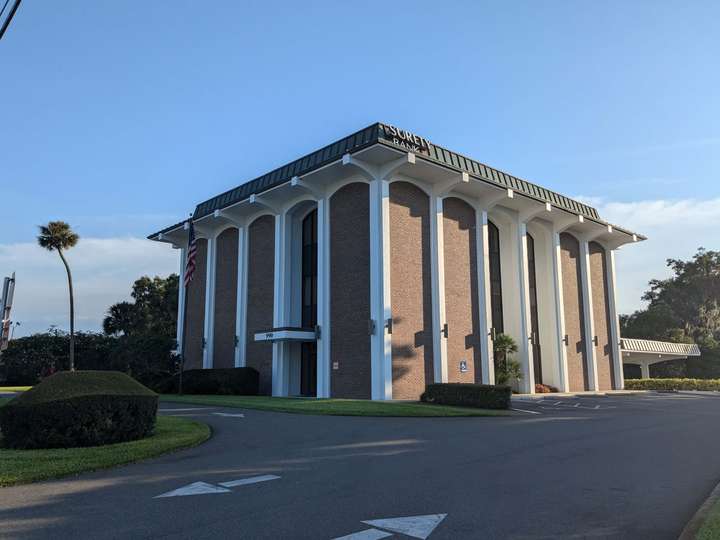 A square bank building with tall arches ending in scallops on all sides