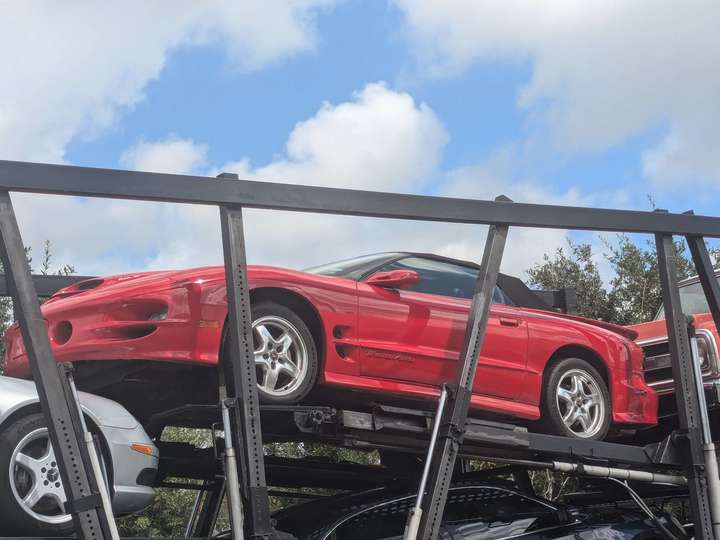 a side shot red 90s sports car on a car carrier trailer