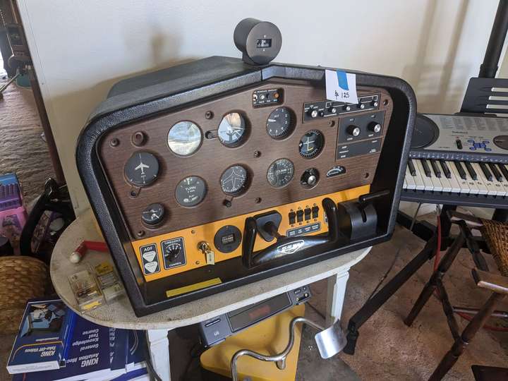 A wood-paneled flight simulator, with a flight stick and many dials.