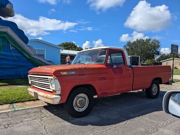 A weathered orange pickup with a white cab roof