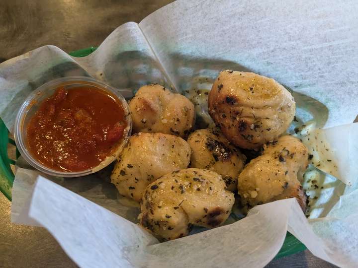 a basket of garlic knots and a cup of sauce