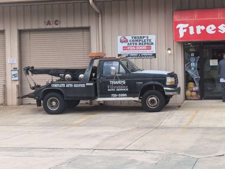 a worn tow truck parked outside an auto repair shop