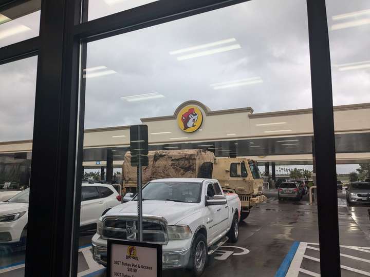 A military truck driving through a large Bucc-ee's gas station