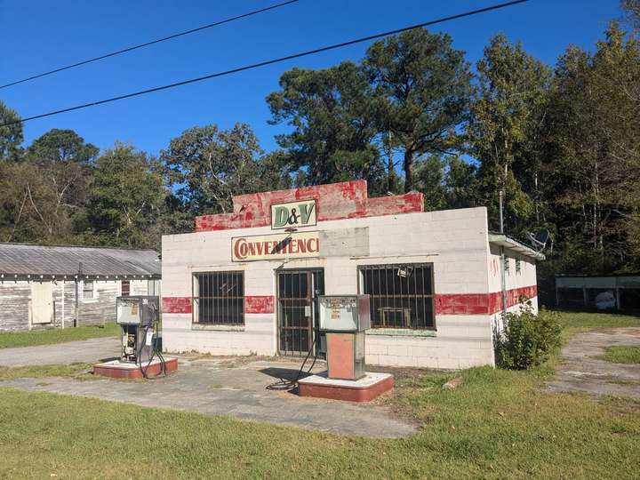 a block gas station building behind two square, vintage pumps