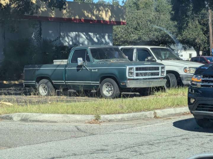 a green pickup truck with a flat rear tire outside an auto repair shop